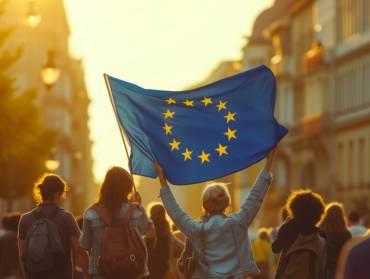 Menschen demonstrieren im abendlichen Gegenlicht, eine Frau hält eine große EU-Flagge hoch