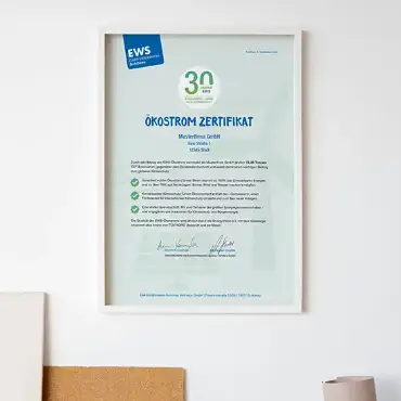 EWS-Ökostrom-Zertifikat im weißem Bilderrahmen am einer Bürowand