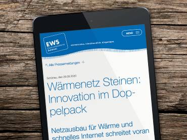 Ein Tablet-Computer auf einem Holztisch, darauf ist eine Pressemeldung zu sehen.