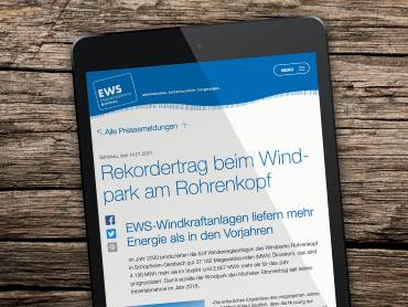 Ein Tablet-Computer auf einem Holztisch, darauf ist eine Pressemeldung zu sehen.