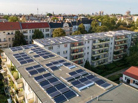 Eine große Wohnanlage mit Solaranlagen auf dem Dach aus der Vogelperspektive