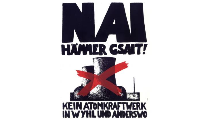 Ein gezeichnetes Atomkraftwerk, das durchgestrichen ist, darum steht der Schriftzug "Nai hämmer gsait! Kein AKW in Wyhl und anderswo"