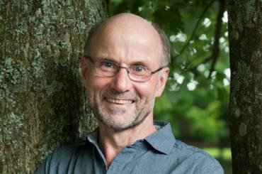 Josef Braun lehnt an einem Baum.