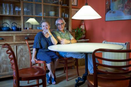 An elderly couple at the table under a large bright lamp.