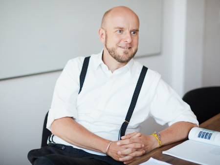 Tobias Kurth am Tisch sitzend, zuhörend, die Hände auf dem Tisch