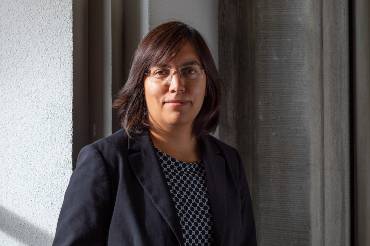 Frau mit Brille und dunklen Haaren vor einer Wand