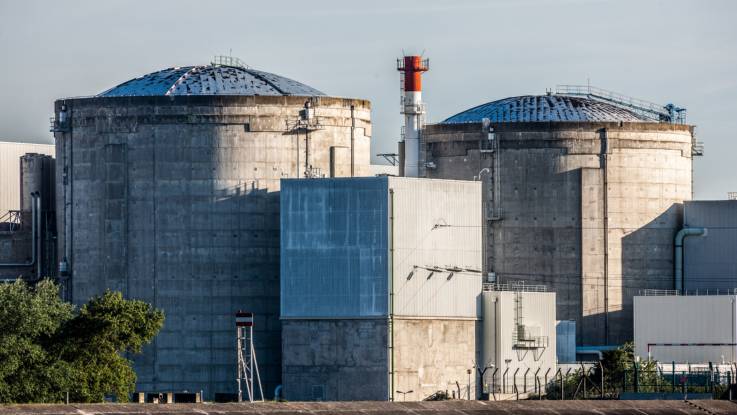 Nahaufnahme zweier sehr alt aussehender Reaktorgebäude aus verwittertem Beton.