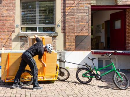 Auf einem Hof steht ein kleines Fahrrad mit einem großen Anhänger.