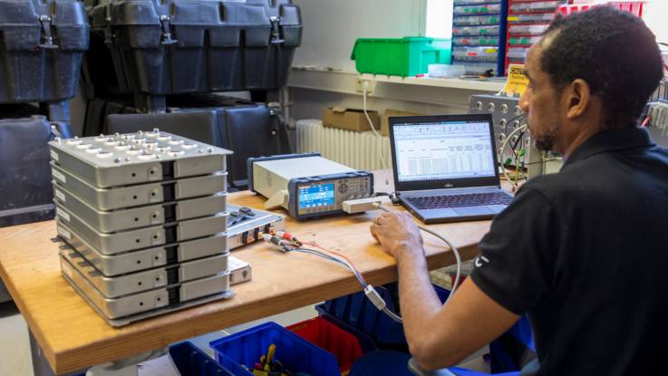An einem Werktisch arbeitet ein Mitarbeiter an elektronischen Geräten.