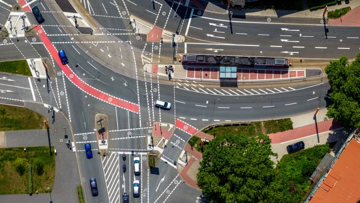 Luftaufnahme zeigt eine großflächige Verkehrskreuzung mit weißen und roten Markierungen.