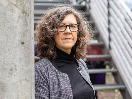 Eine Frau mit langen grau-melierten Locken spricht lebendig gestikulierend.