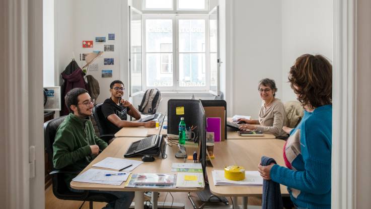 A glimpse into the cooperative‘s office. Three employees sit around a large table, the fourth person leans against the door.