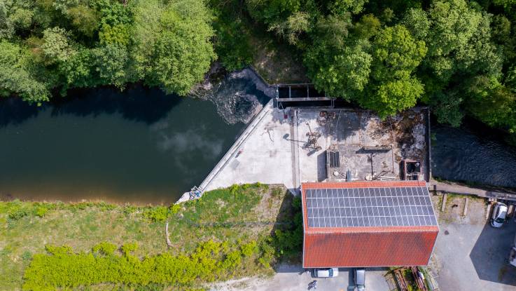 Eine grundüberholte Wassermühle aus der Vogelperspektive: auf der Zulaufseite ist das Wasser aufgestaut. 