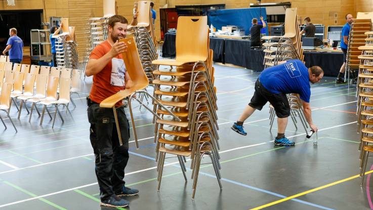 Die Halle bei Tageslicht: Abbauhelfer haben die ersten Stuhlreihen bereits zu kleinen Türmen aufgestapelt.