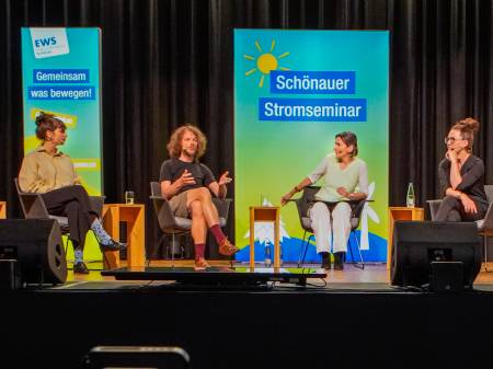 Auf dem Podium sitzen vier Personen und diskutieren angeregt miteinander.