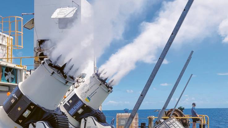 Auf einem Schiff sind zwei kanonenartigen gen Himmel gerichteten Zylinder installiert,  aus ihnen steigt Wasserdampf auf.