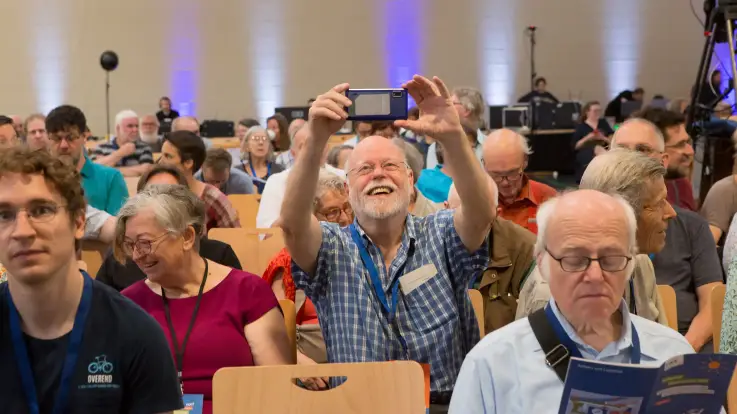 Einer der Zuschauer hat sich aufgerichtet, um ein klares Sichtfeld für eine Aufnahme mit seinem Smartphone zu haben. 